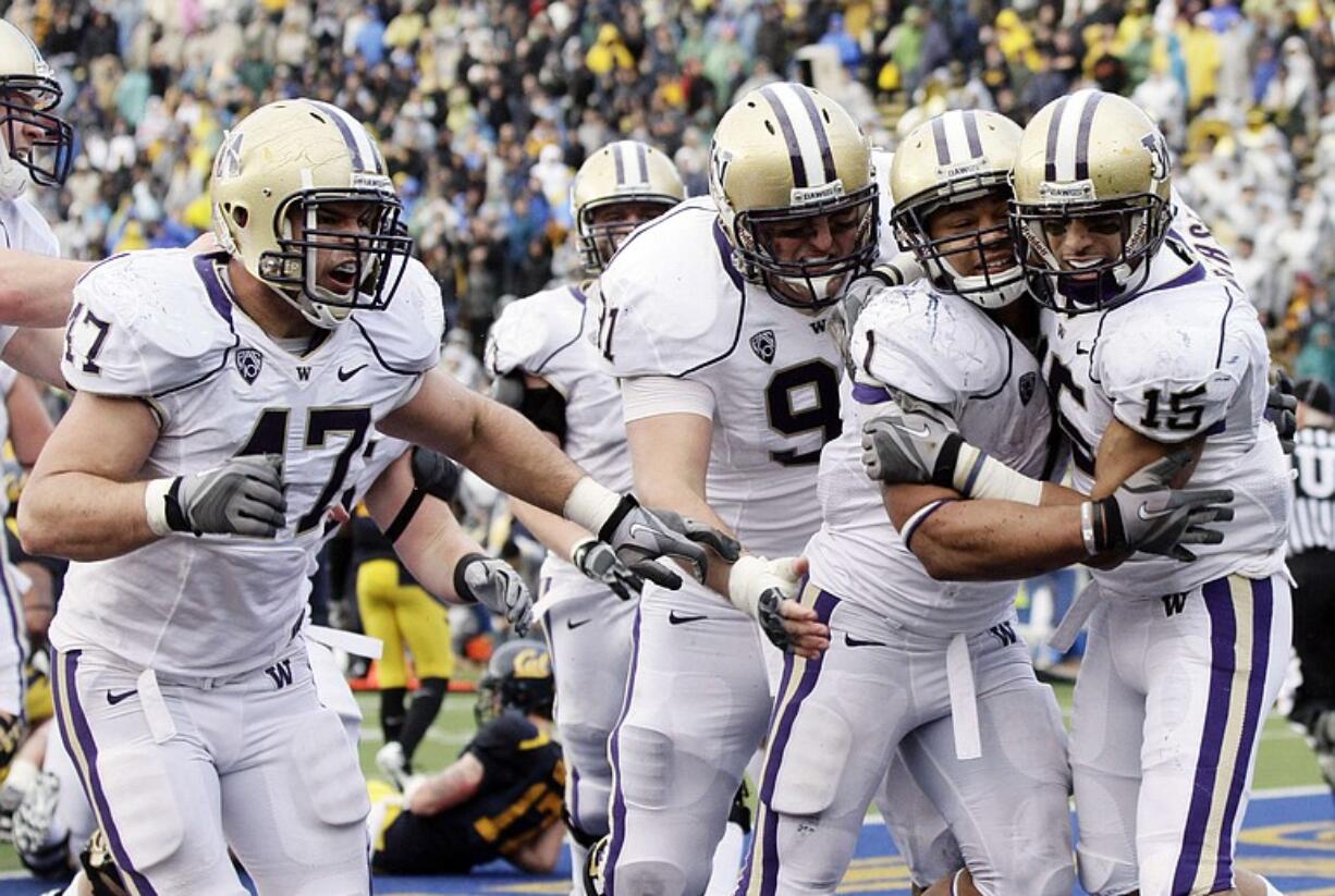 Washington running back Chris Polk, second from right, is mobbed by teammates in the end zone after scoring the game-winning touchdown on a 1-yard run as time expired.