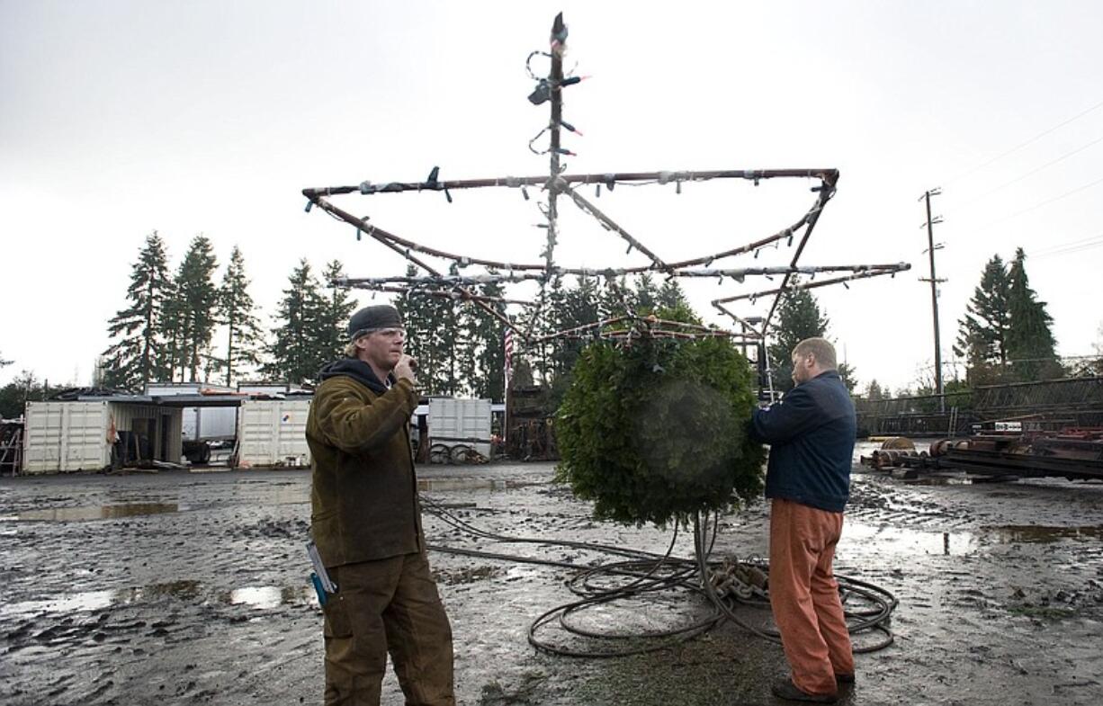 Will Barnes, left, and Rick Smith of DeWitt Construction make sure the Christmas tree and 6-foot-wide star are secure Wednesday before the 130-foot crane boom is raised.