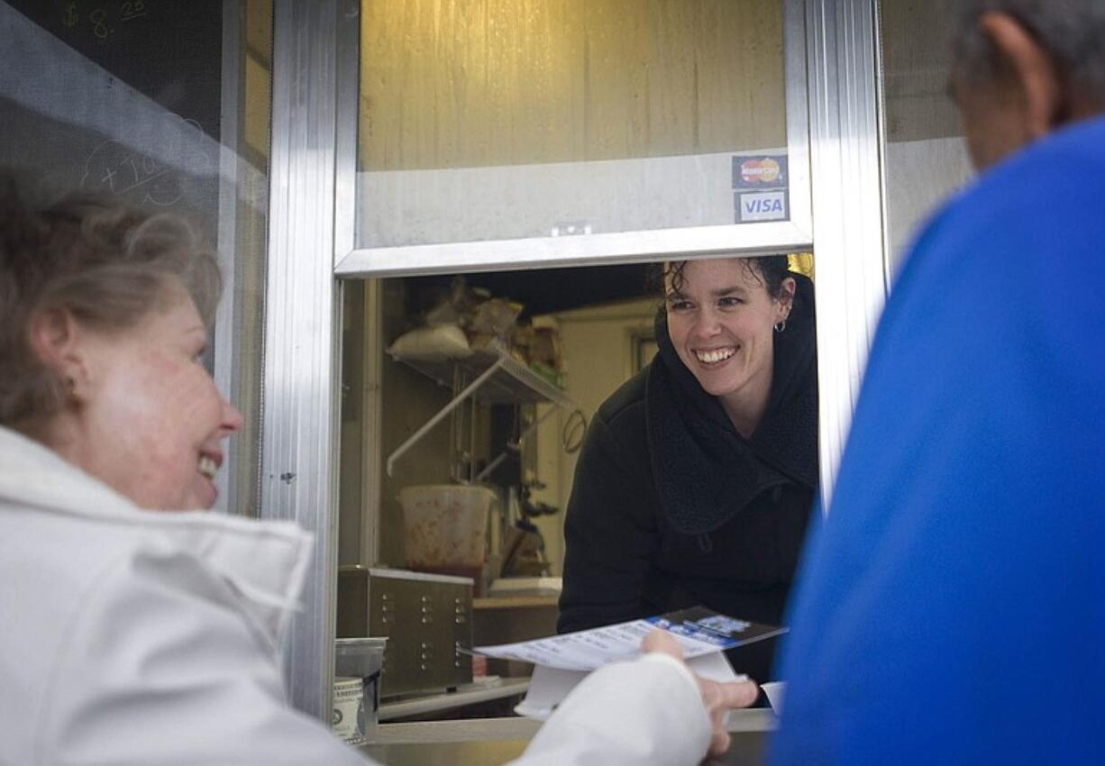 MaKayla Hopper, owner of Holy Smoke ... It's Big B's BBQ, serves Christine and Tony Piazza of Battle Ground a pulled pork sandwich from her food cart Tuesday.