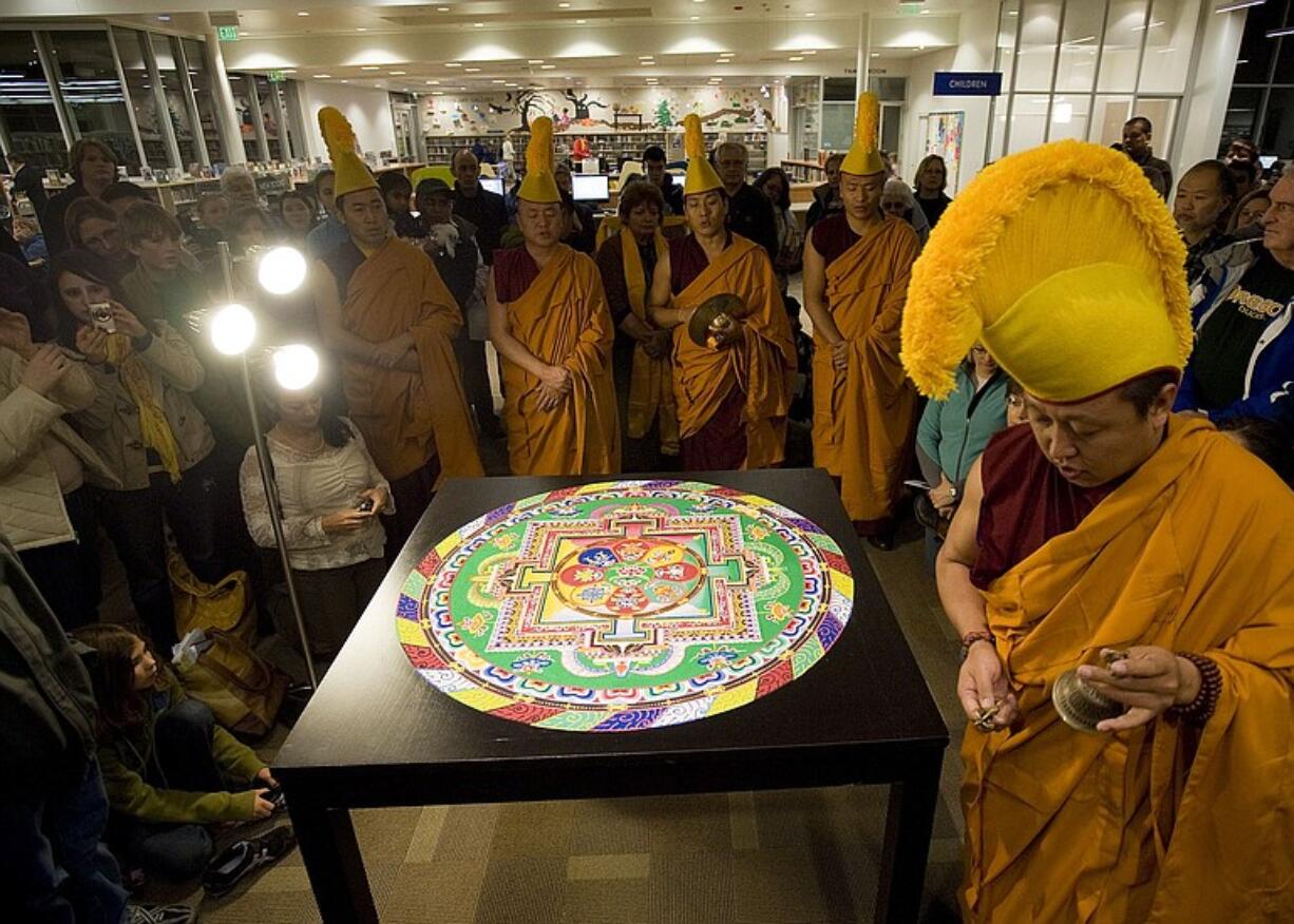 After performing ritual chants for a crowd at the Cascade Park Community Library, Tibetan Buddhist monks prepare to brush away their intricate sand mandala, meant as a blessing and symbolizing the impermanence of life.