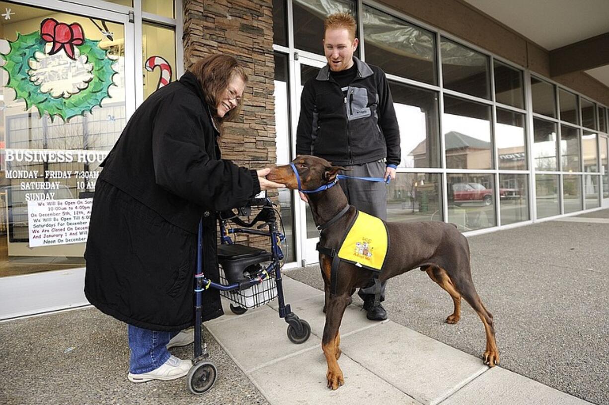 Tyson, a 13-month-old Doberman pinscher, who was born with carpus valgus, or deformed front legs, offers his nose in greeting to Linda McMurtry of Vancouver, while foster owner Bryan Andrews holds the dog's leash.