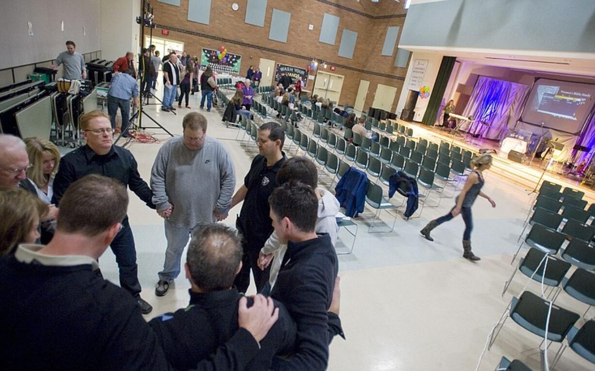 The Summit View Church leadership group and volunteer core pray before a Sunday service inside their temporary home at Felida Elementary School while a nearby building is remodeled.