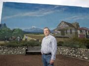 Garry Brown stands in front of the historical mural at Orchards Plaza.