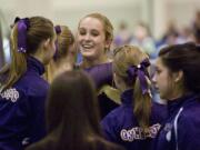 Columbia River's Jordan Hess is congratulated by teammates after competing on the uneven bars at the Class 3A state championships despite a torn ACL.