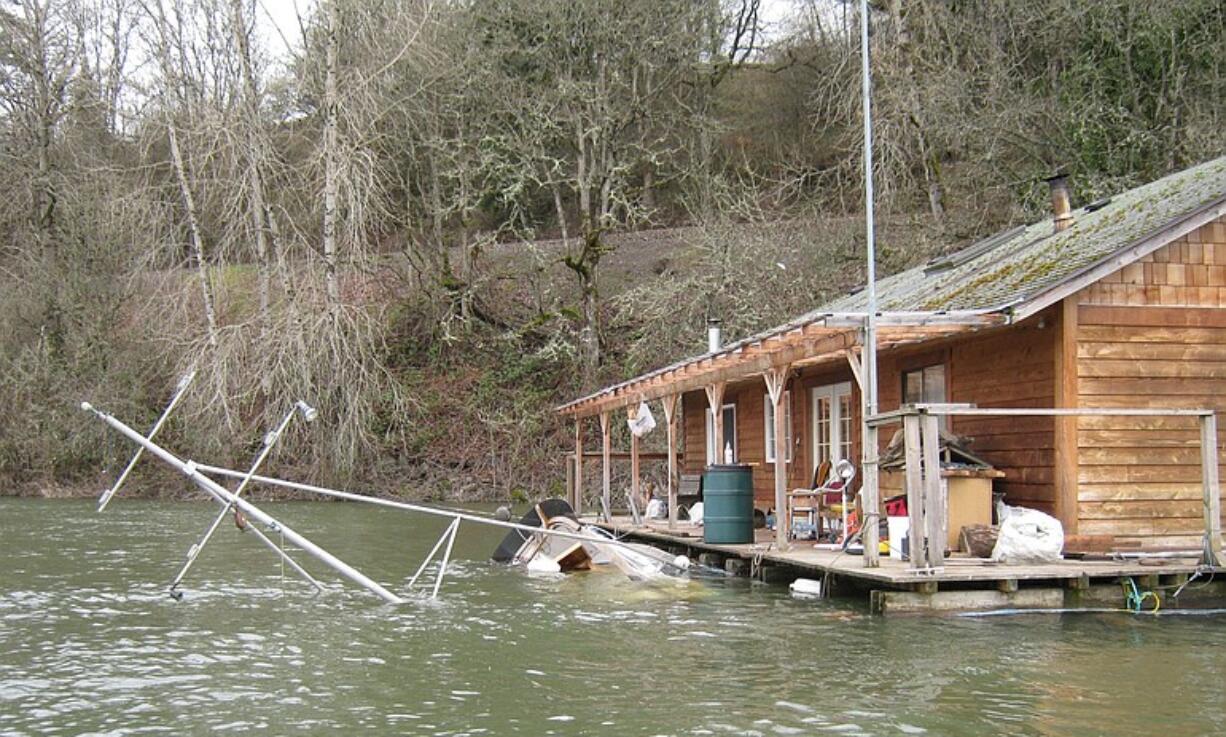 A wayward houseboat and sunken cruiser rest in Lake River on Wednesday afternoon.