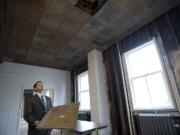 Michael True holds an original two-foot-square pressed-tin ceiling panel Friday while explaining renovation plans in the east wing.