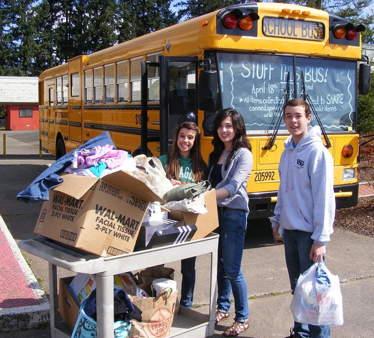 Pleasant Valley Middle School student body leaders, from left, Brielle Lindsay, Keiko Inouye and Jordan Halverson load food and other items aboard a school bus for the trip to SHARE, a Vancouver-based charity for the homeless and needy.