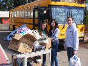 Pleasant Valley Middle School student body leaders, from left, Brielle Lindsay, Keiko Inouye and Jordan Halverson load food and other items aboard a school bus for the trip to SHARE, a Vancouver-based charity for the homeless and needy.