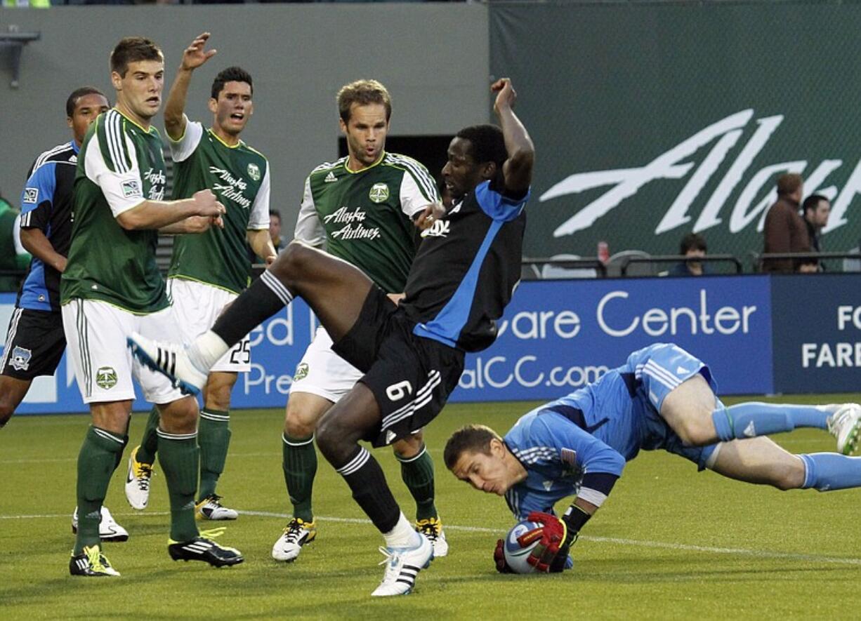 Timbers defenders, from left, David Horst, Steve Purdy and Freddie Braun watch as Timbers goalkeeper Troy Perkins, right, dives in to stop a shot by San Jose Earthquakes defender Ike Opara (6).