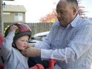 Jerry Gowen earned his MBA degree this year after four years of night classes at Washington State University Vancouver. Here, he straps a helmet on his son, Scott, 20 months old, outside his Felida home.