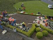 About 20 volunteers from the Master Gardeners Foundation of Clark County plant approximately 2,500 flowers below the Welcome to Washington sign along northbound Interstate 5 on Saturday.