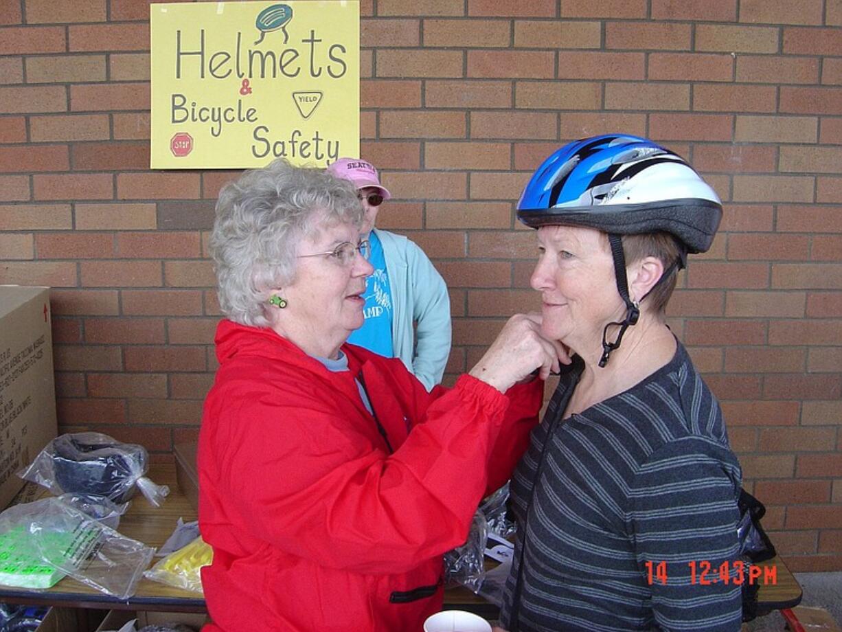 Marion Swenson adjusts a helmet for Lanell Wells at the Fircrest Neighborhood bike rodeo.