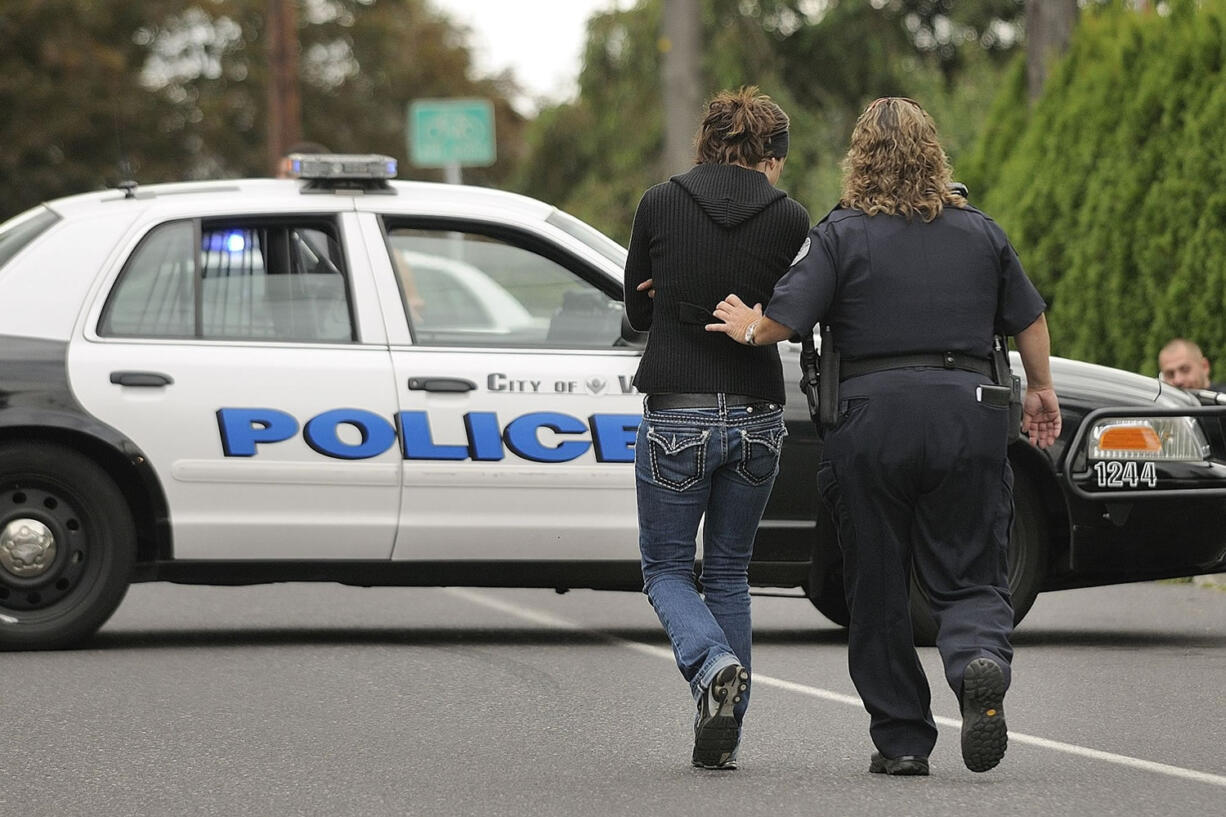 A Vancouver police officer escorts a person of interest to a police car at a shooting incident on Sept.