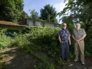 Concerned neighbors Jim Faull, left, and Ed McMillan stand in front of an abandoned home that they say is a haven for critters and an eyesore. The city says it lacks the money to do much for most junky houses.