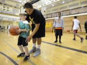 Nate Brown, 9, gets instruction from Hudson's Bay senior Jahmile Sipaia, 17, on the final day of Eagle Hoop Camp at Hudson's Bay High School Thursday July 14, 2011 in Vancouver, Washington. In the background wearing the sweatshirt is Erkinson Bossy, 16, a Hudson's Bay basketball player who was helping out at the camp as well.