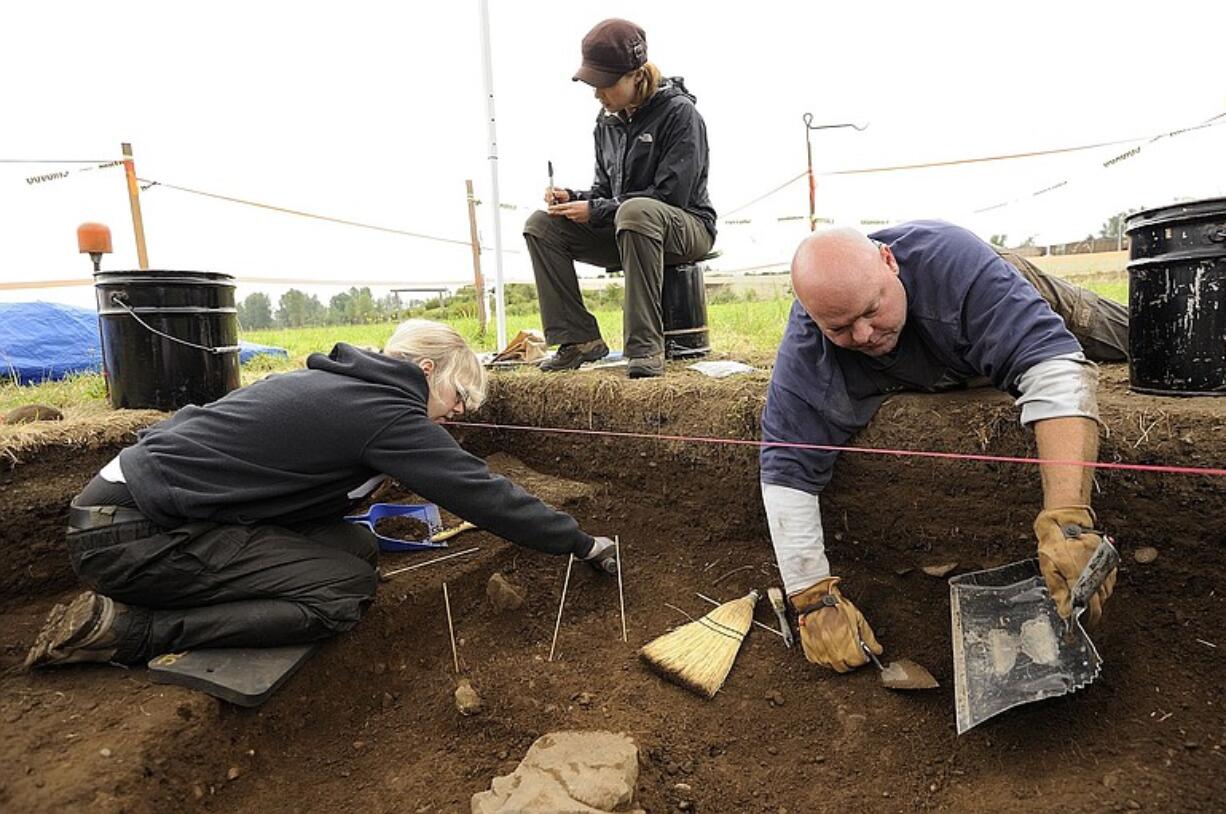 Cara O'Neil, center, a Portland State University grad student, logs information while WSU Vancouver student Sarah O'Keefe, left, and Bruce Schneider, a Northern Arizona University grad student, carefully excavate at a site in the workers' village Tuesday at the Fort Vancouver National Historic Site.