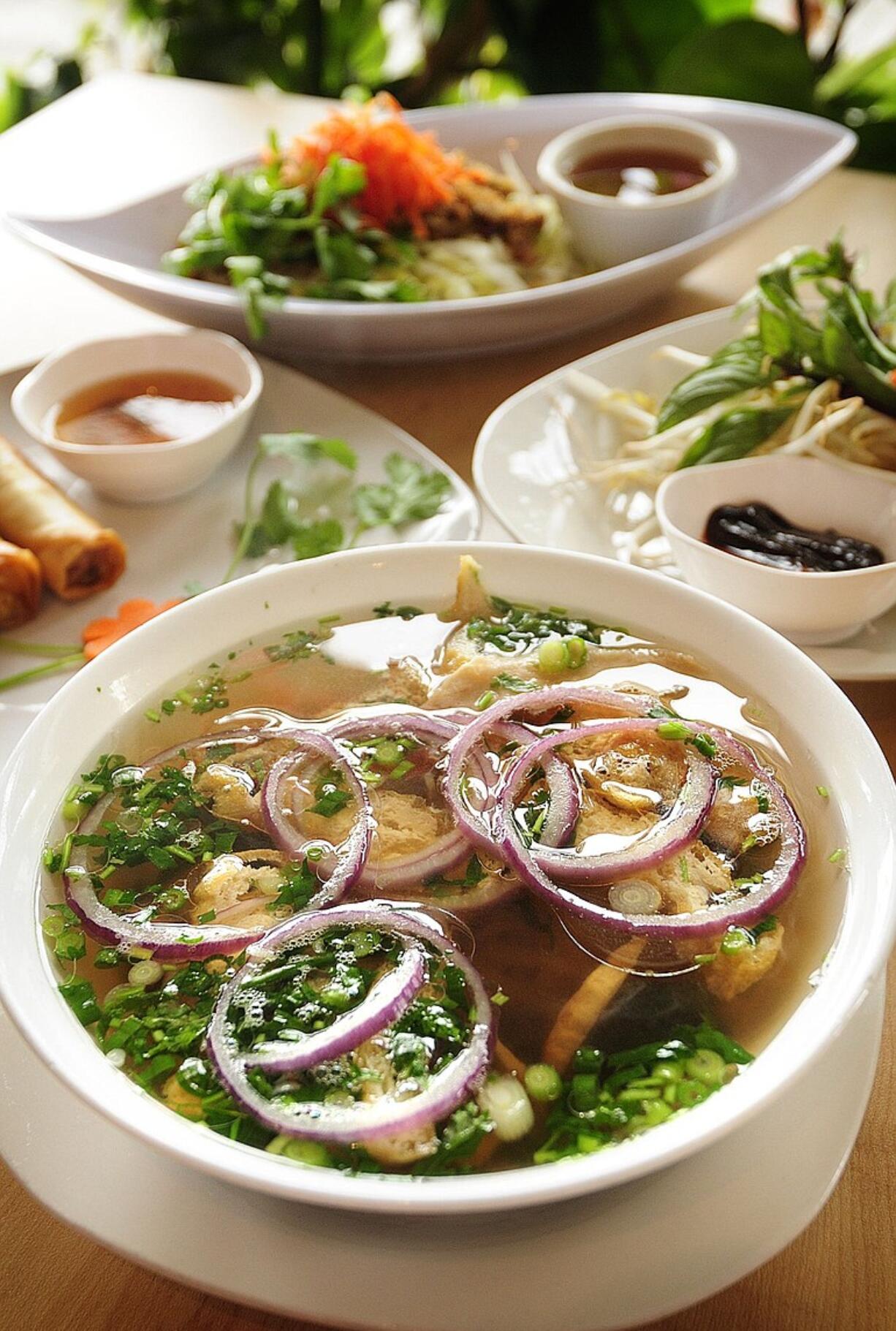 Vegetarian Pho, foreground, vegetarian spring rolls, left, and Lemon Grass Vegan Soy Chicken over rice stick noodles are served at the Bamboo Hut restaurant in Vancouver.