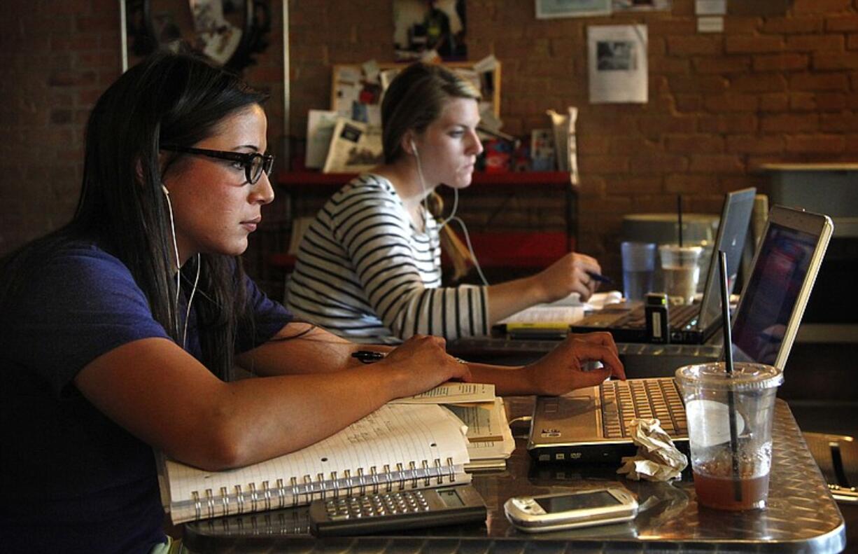 University of Texas-Dallas grad student Tamara Robertson, left, uses her laptop, calculator and phone to study for a summer course at The Pearl Cup on July 2 in Dallas.