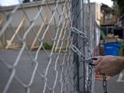 Jacob Dye, a technician assistant with PuroClean Portland, locks up a gate for the day at Rolling Creek Apartments.