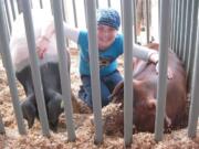 Ridgefield: Tayte Tobison-Hanchett sits with her pigs -- Hamilton, right, and The Evil Doctor Porkchop -- that she sold at the Junior Livestock Auction at the Clark County Fair.