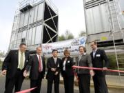 At a ceremony to dedicate new cooling towers at WaferTech, company President KC Hsu, center, cuts the ribbon with help from Camas Mayor Scott Higgins, from left, Sen.