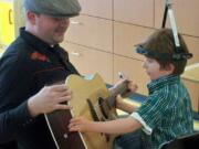 Burnt Bridge Creek: Beckem Nimmo, 5, right, watches Nick Etlin play his guitar at Shriner's Hospital during a music therapy session hosted by Owl Be Better With Music, a nonprofit started by Madeline Bennett, a senior at Heritage High School.