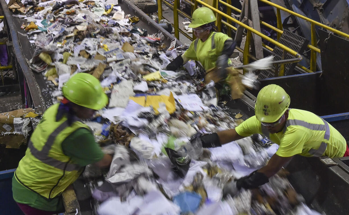 Workers sort waste as the conveyor belt moves recyclables at the Waste Management's  Elkridge Material Recycling Facility on Thursday in Elkridge, Md.