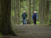 Camas residents Helen and Jay Elder, and their dog, Wesley, walk the trails along Round Lake on Wednesday.