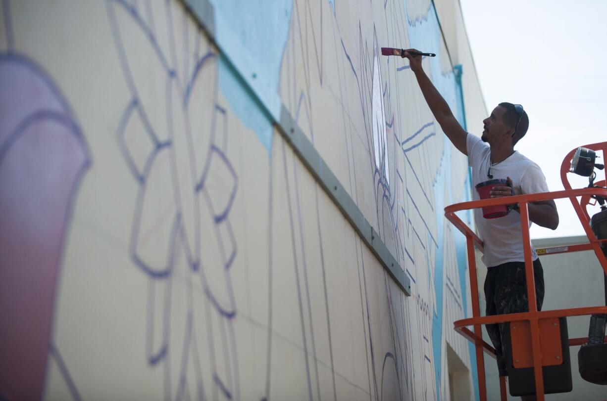 Portland artist Michael Feliz works on a mural Friday for this year's Summer of Murals contest on a wall of Luepke Flowers in downtown Vancouver.