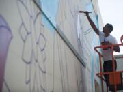 Portland artist Michael Feliz works on a mural Friday for this year's Summer of Murals contest on a wall of Luepke Flowers in downtown Vancouver.