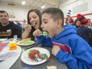 First-grader Skyler Dassinger takes a giant bite of green scrambled eggs with his mom, Cassandra Gonzalez, on Wednesday at the annual Green Eggs and Ham breakfast at Walnut Grove Elementary School in Vancouver.