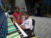 Edna Flores, center, and Christina Arales examine a piano in front of the Vancouver Community Library on Friday.