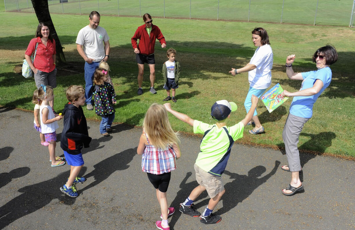 Participants warm up before a StoryWalk session led by Three Creeks librarian Barbara Jorgenson, right, and youth librarian Heather Rhone, second from right, Monday at H.B.