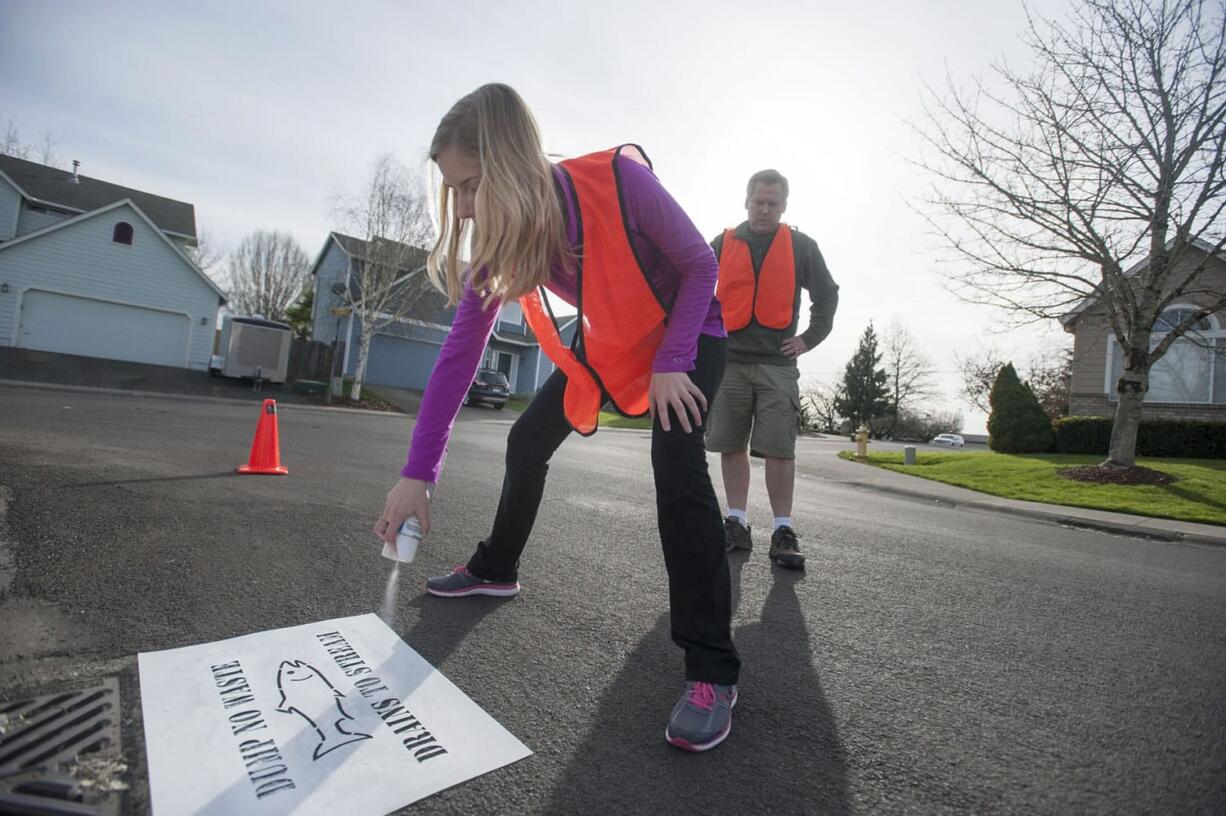 Kati Cooke, with her father Mike, stencils &quot;Dump No Waste&quot; near a Salmon Creek storm drain.