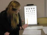 Abigail Coleman, 15, a health science careers student at Battle Ground High School, points to the vision chart while she and other high school students screened students' vision at Daybreak Primary School on Monday.