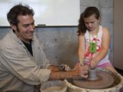 Pottery instructor Chuck Masi helps 7-year-old Kaylee Gibbs of Vancouver form a clay pot on the wheel during the Marshall Community Center's family fun day Saturday.