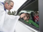 Gavin Waggoner, in green, gets smudged from the comfort of his car seat by the Rev. Tom Warne.