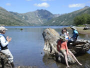 Leaning against a blown-down tree on the banks of Coldwater Lake, Cynthia Gardner, a U.S. Geological Survey research geologist, weaves the story of the May 18, 1980 eruption of Mount St. Helens. Middle school girls settle on a tree stump in the lake listen.