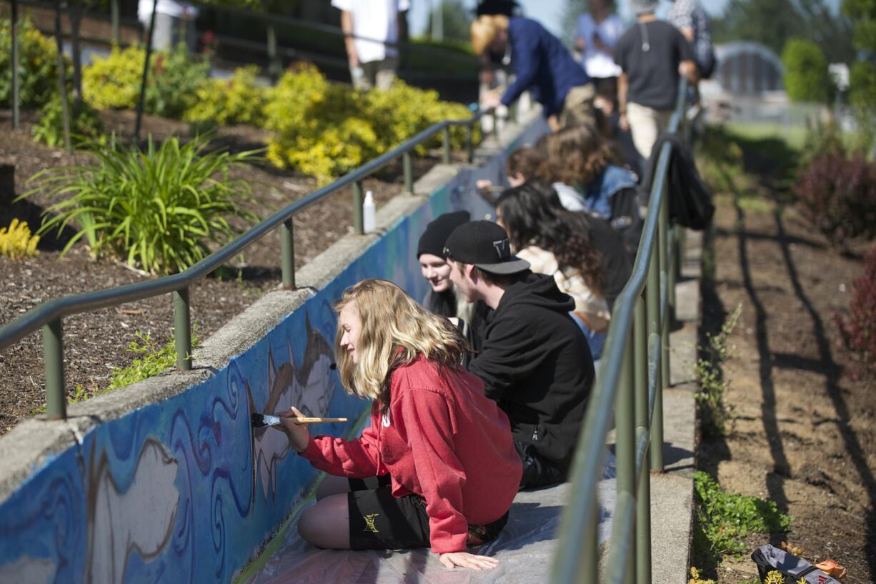 Sadie Spindler, 16, front, along with other Legacy High School students, paints a salmon mural Friday. Artist Toma Villa, a tribal member of the Yakama Nation, is working with students at Legacy High School to create a school mural.