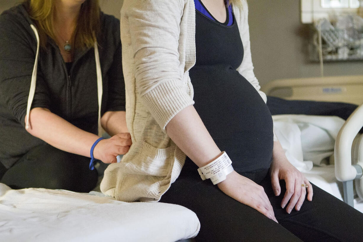 Doula Julia Schetky applies pressure to Brittany Lawrence's sacrum to help with contractions and back pain during labor.