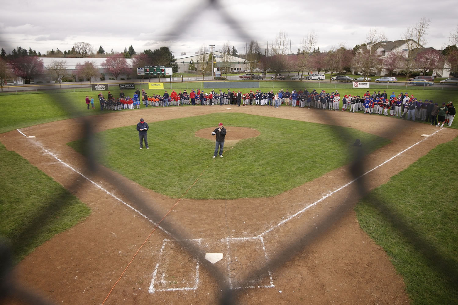 Roman Schauer, center, information officer for Hazel Dell Little League, helps conduct the opening-day ceremonies.