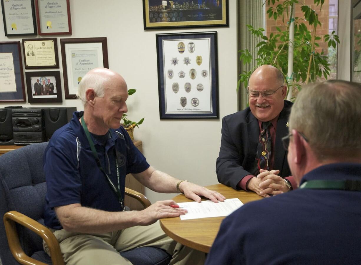 Clark County Sheriff Garry Lucas swears in former detective Ron Epperson and a retired prosecuting attorney who asked not to be named as volunteer cold case detectives last week.