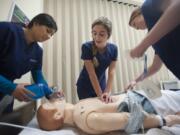 Nursing students Imrin Uppal, from left, Olivia Schmitz and Averie Henry practice monitoring and responding to patients in the state-of-the-art nursing station at Henrietta Lacks Health and Bioscience High School in Vancouver on Thursday.