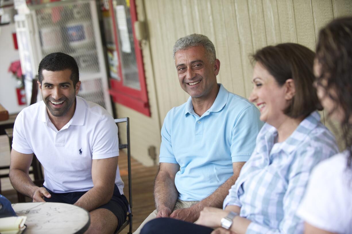 Kourosh Zamanizadeh, from left, and his parents, Mike and Rose Zamanizadeh, sit on the Skamania General Store's porch with store manager Michelle Sobaski, right.