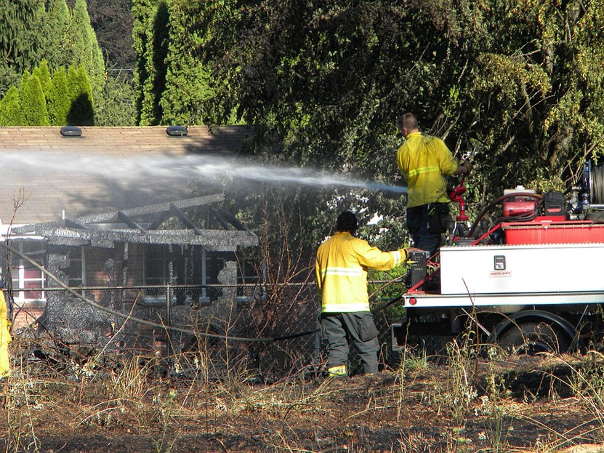 Vancouver firefighters soak down ruins of a burned backyard shed Tuesday afternoon from a vacant property in the Marrion neighborhood.