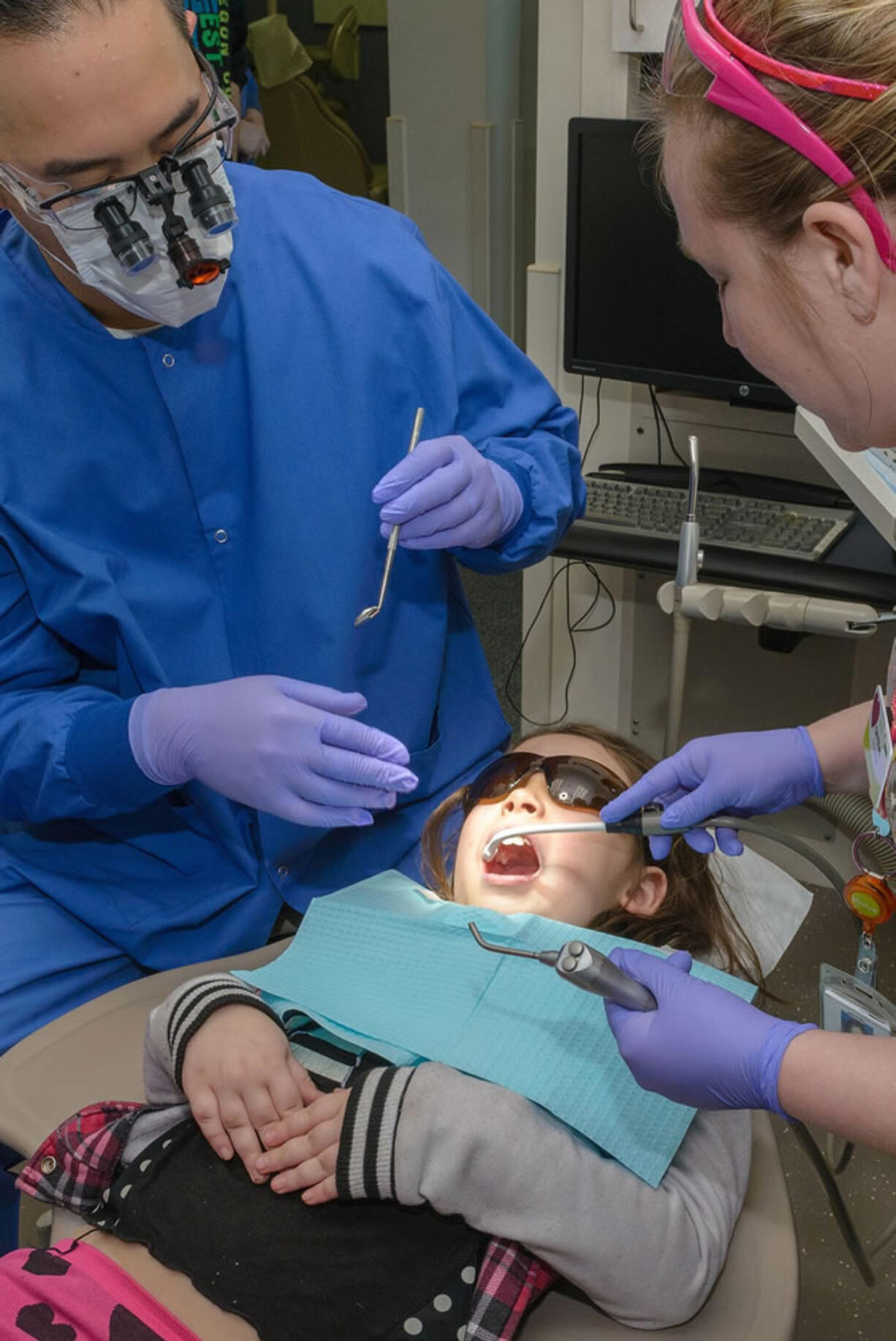 East Vancouver: Kaiser Permanente dentist Felix Lee, left, and dental assistant Crystal Schnacky provide August Ebalaroza, 7, with free dental care as part of Give Kids a Smile on Feb.