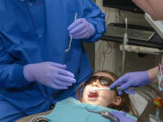 East Vancouver: Kaiser Permanente dentist Felix Lee, left, and dental assistant Crystal Schnacky provide August Ebalaroza, 7, with free dental care as part of Give Kids a Smile on Feb.