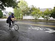 A bicyclist rides northbound past a sharrow marking on Columbia Street near West 23rd Street.