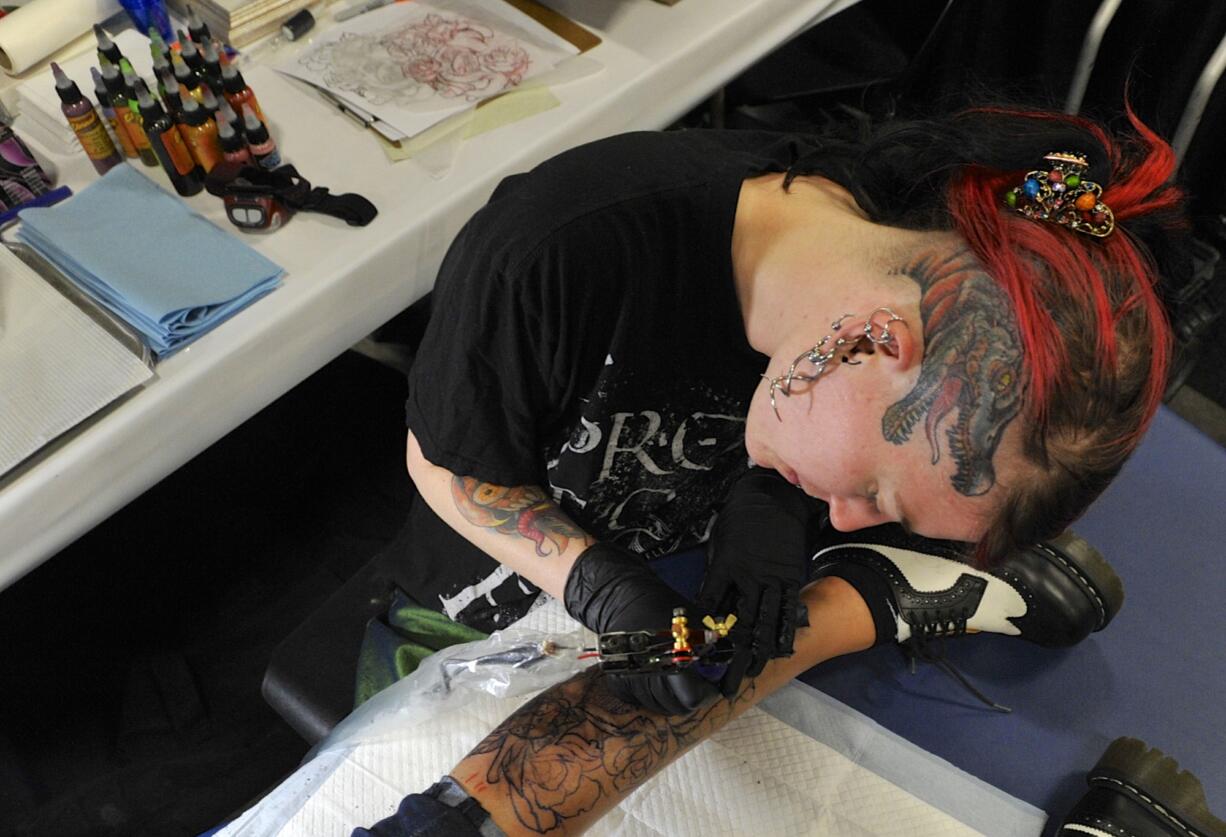 Serina Malec works on a tattoo on Cecilia Flores' leg Sunday during the Northwest Ink tattoo convention at the Clark County Event Center at the Fairgrounds in Ridgefield.