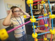 Jesse Oliver, left, and other kids build a Tinkertoys tower Tuesday afternoon at the Clinton and Gloria John Clubhouse.